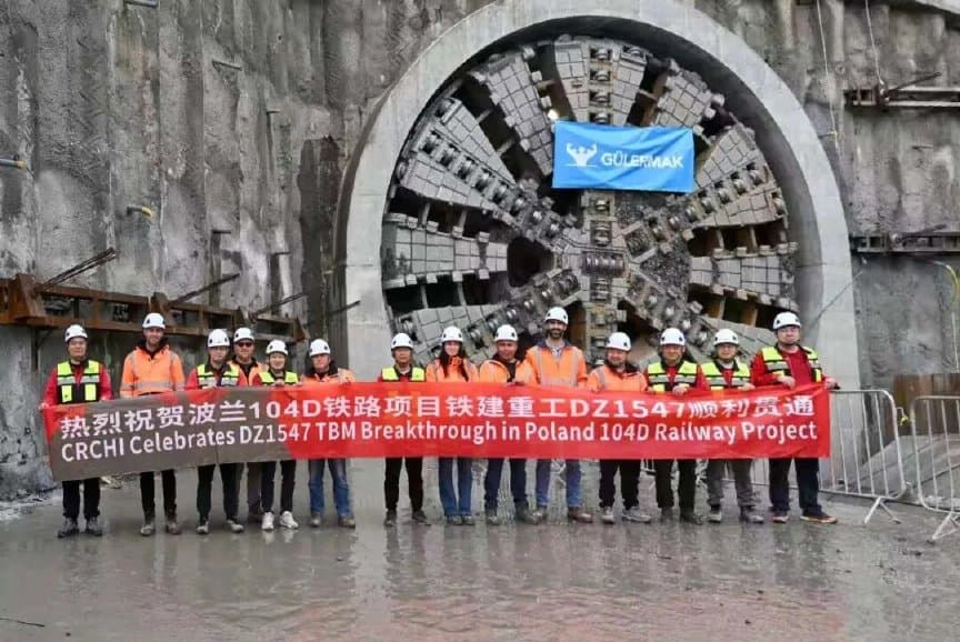 Project team in PPE assembled in front of the TBM cutterhead at the breakthrough portal with the celebratory CRCHI breakthrough banner held in front of the crew