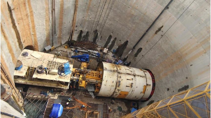 Top-down view of the double-shield TBM body and trailing gear in the launch shaft with crew working alongside